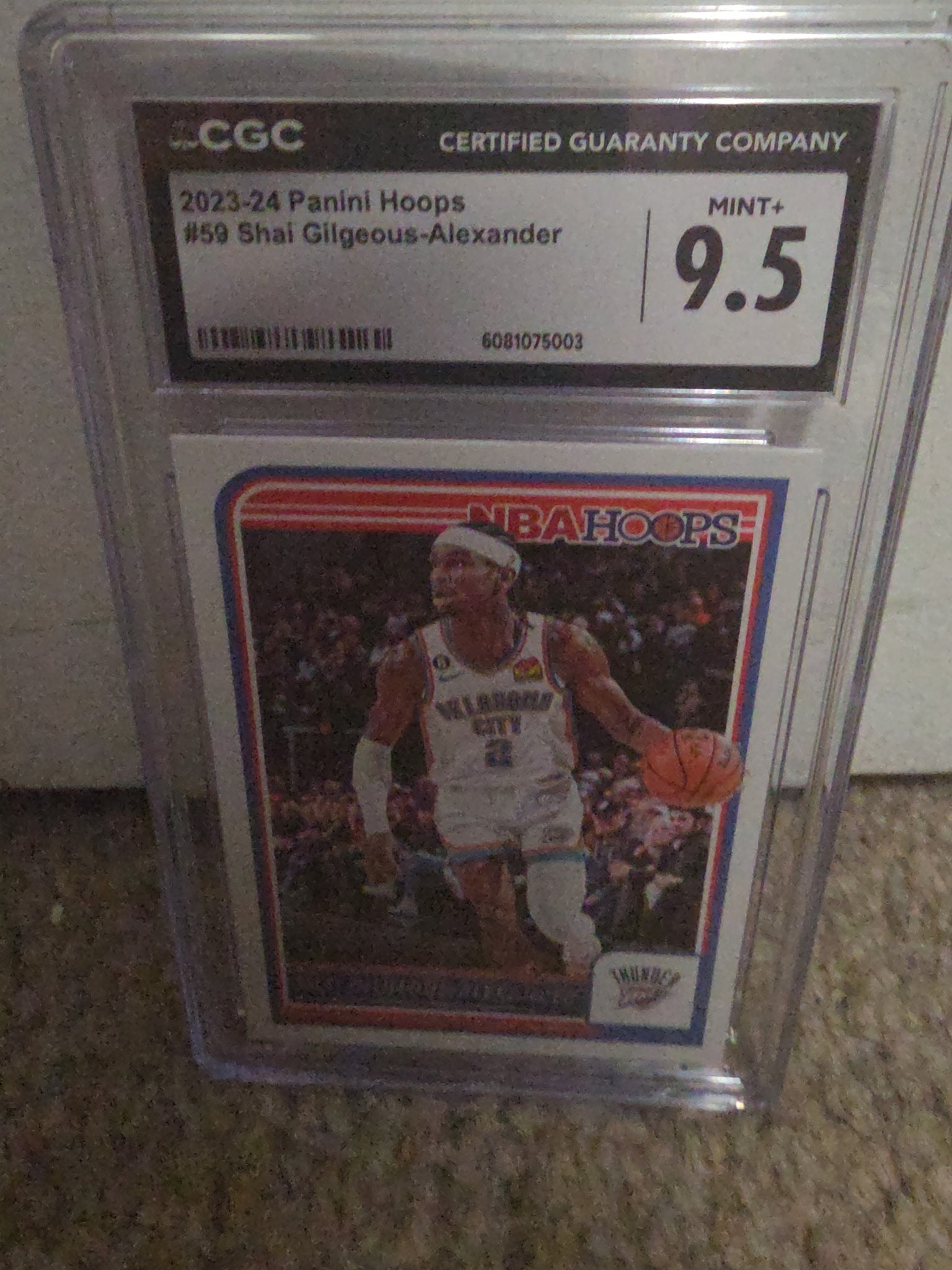 Basketball trading card with CGC grading label on a carpeted floor