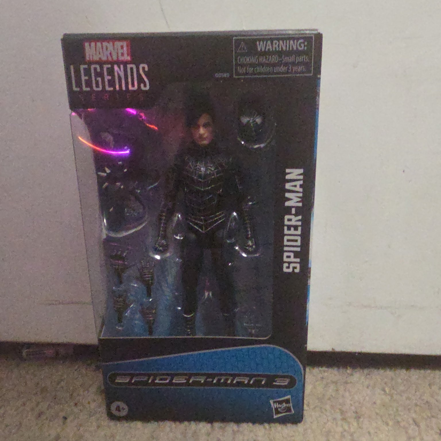 Marvel Legends Spider-Man action figure in packaging on a carpeted floor.